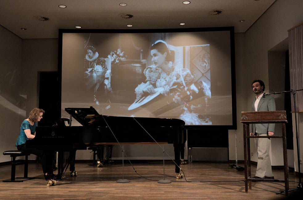 Prof. Karola Theill (Klavier) und Martin Rieck (Gesang) bei der Aufführung von „Doña Maria’s Song“ parallel zur zugehörigen Szene aus dem Film „The Sea Hawk“ (1940) im Rahmen eines multimedialen Konzertabends an der Hochschule für Musik und Theater Rostock, 27. Juni 2024 